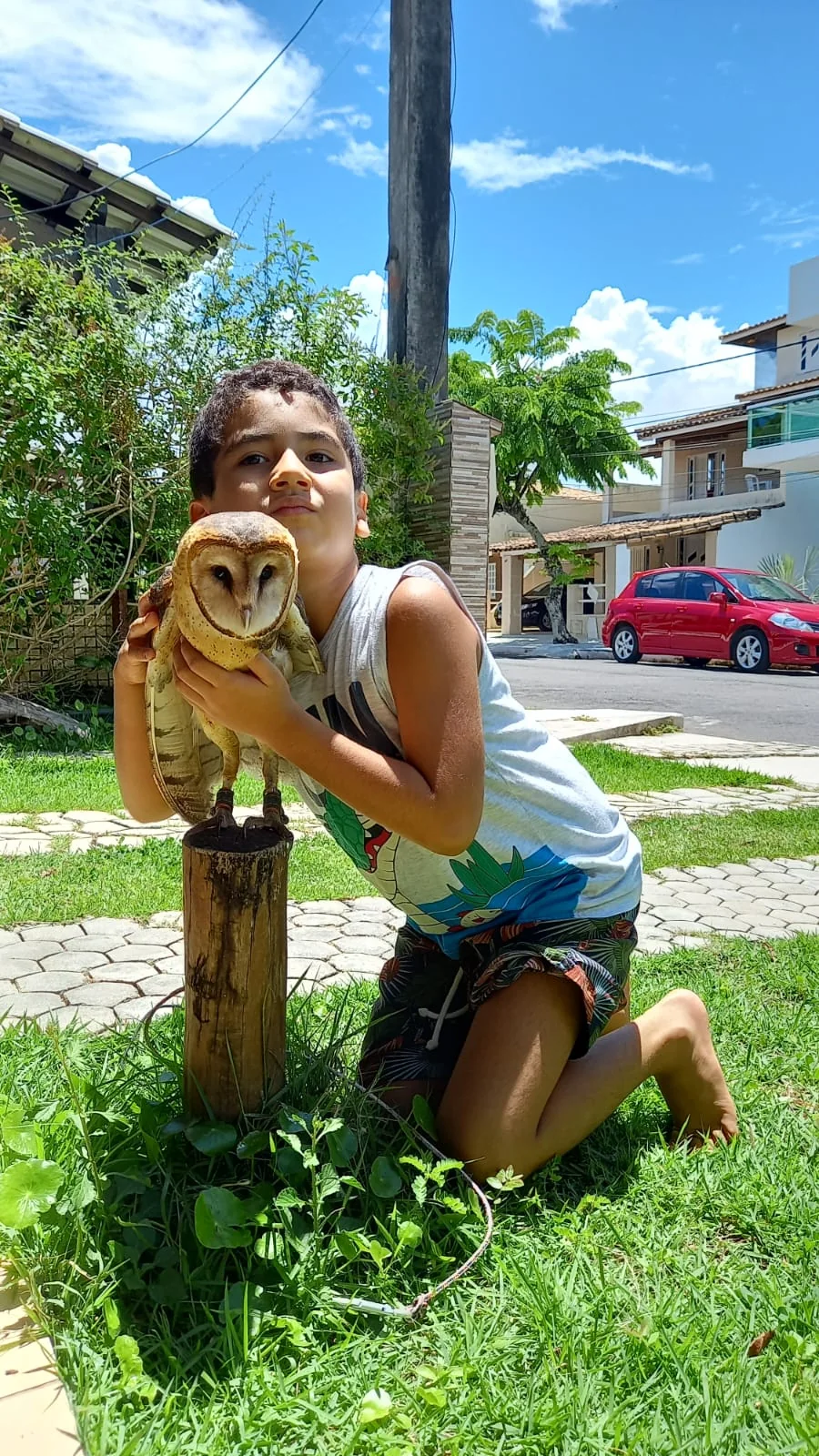 Criança sorrindo perto de uma coruja suindara